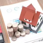 Ein Hausmodell und Münzstapel